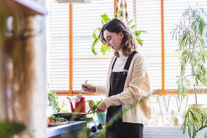 観葉植物が飾られたキッチンで料理をする女性