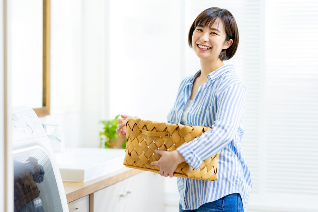 ランドリールームで洗濯篭を持つ笑顔の女性
