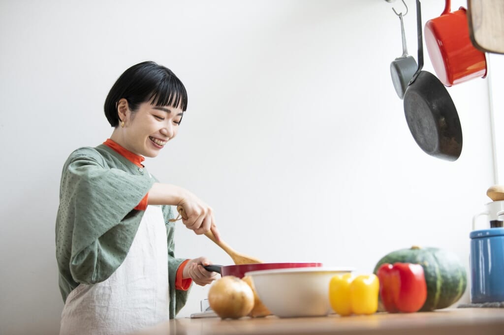 笑顔でキッチンで調理をする女性
