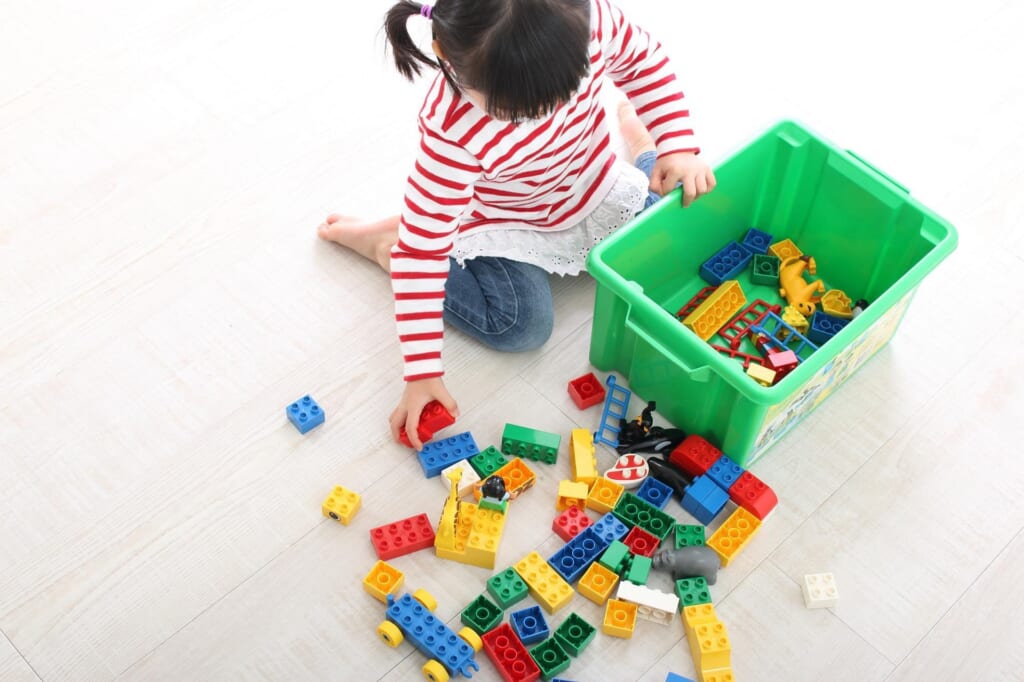 ブロックを箱に片付ける子供