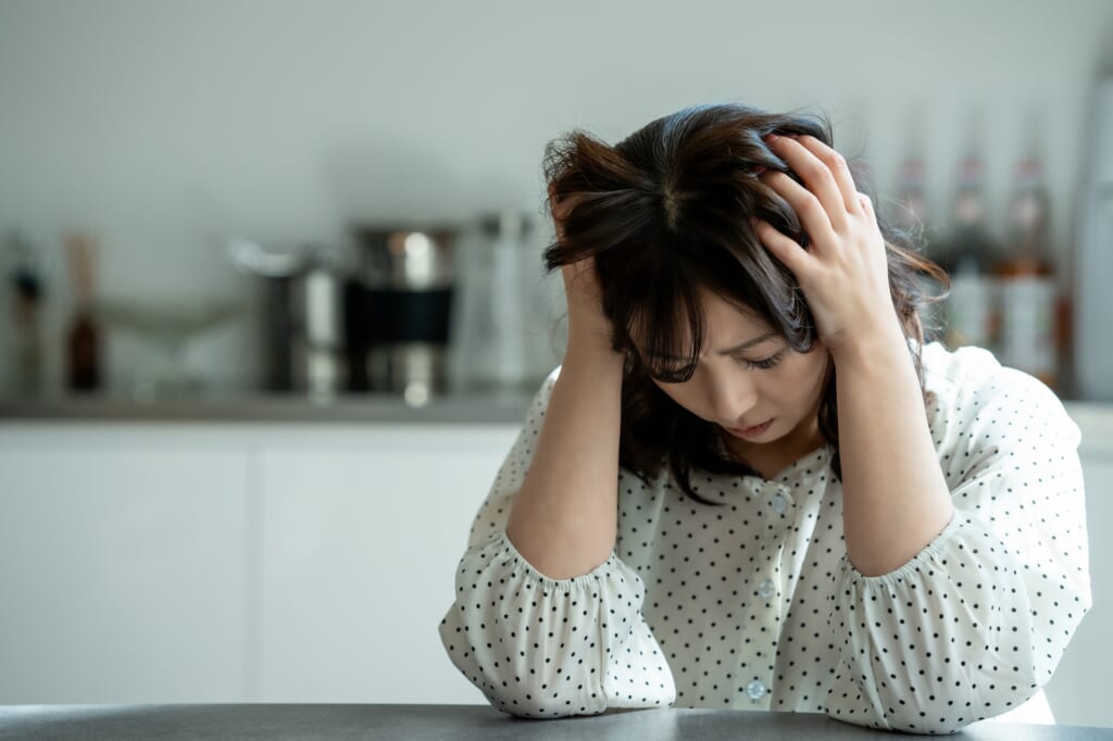 頭を抱えて考え込む女性