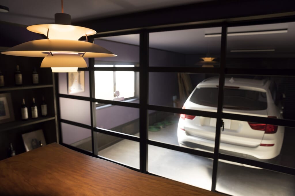 部屋からの明かりとビルトインガレージに停車する車