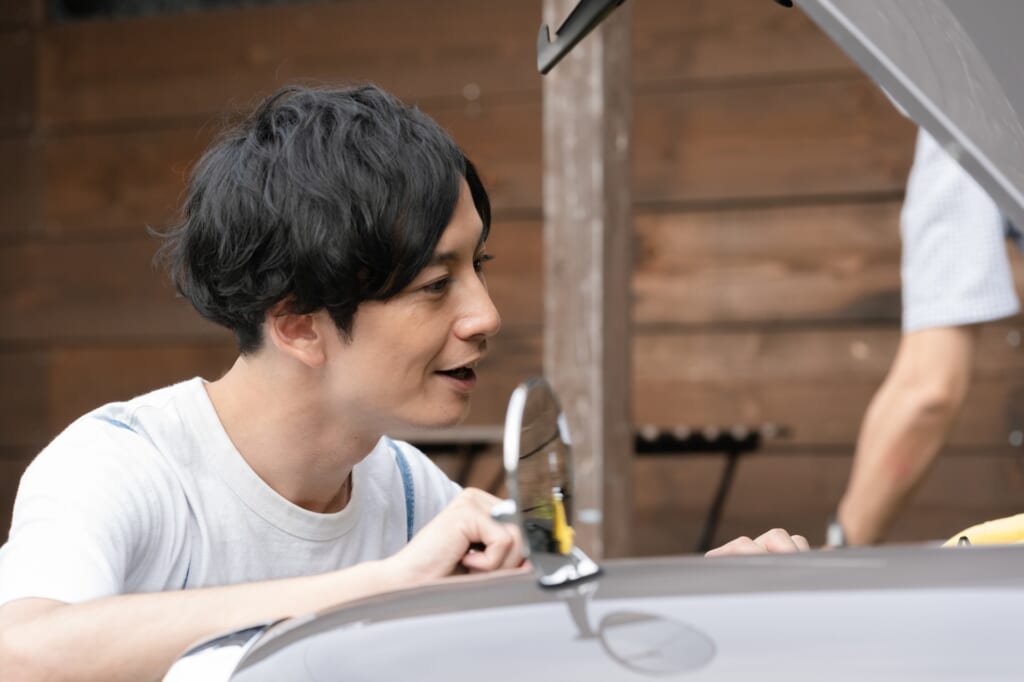 車のエンジン部分を覗く男性