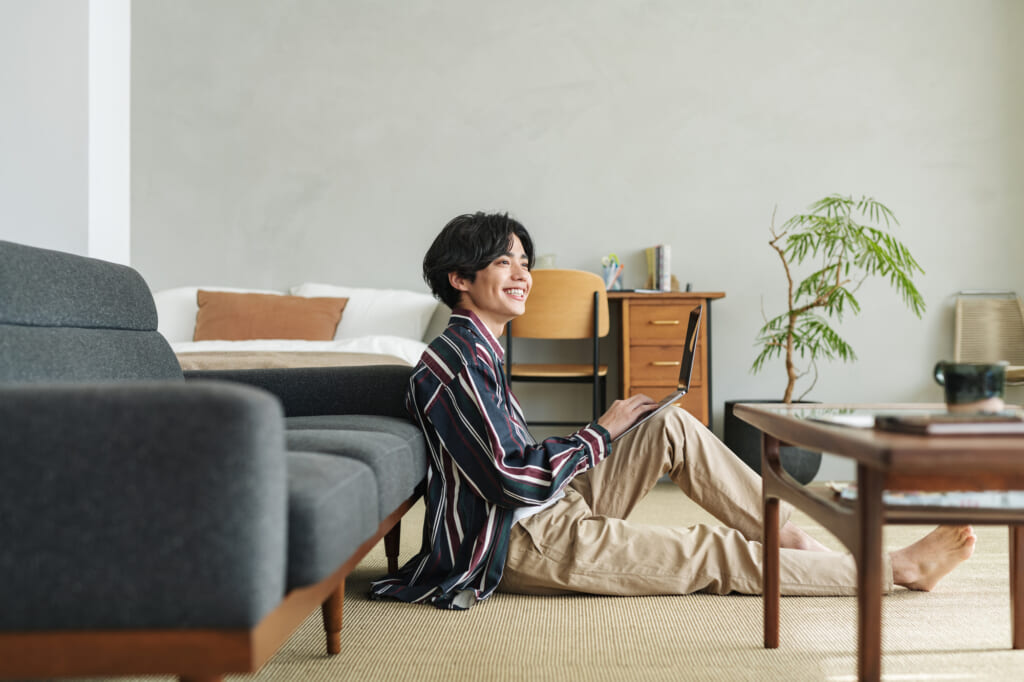 PCを持って笑顔でくつろぐ男性
