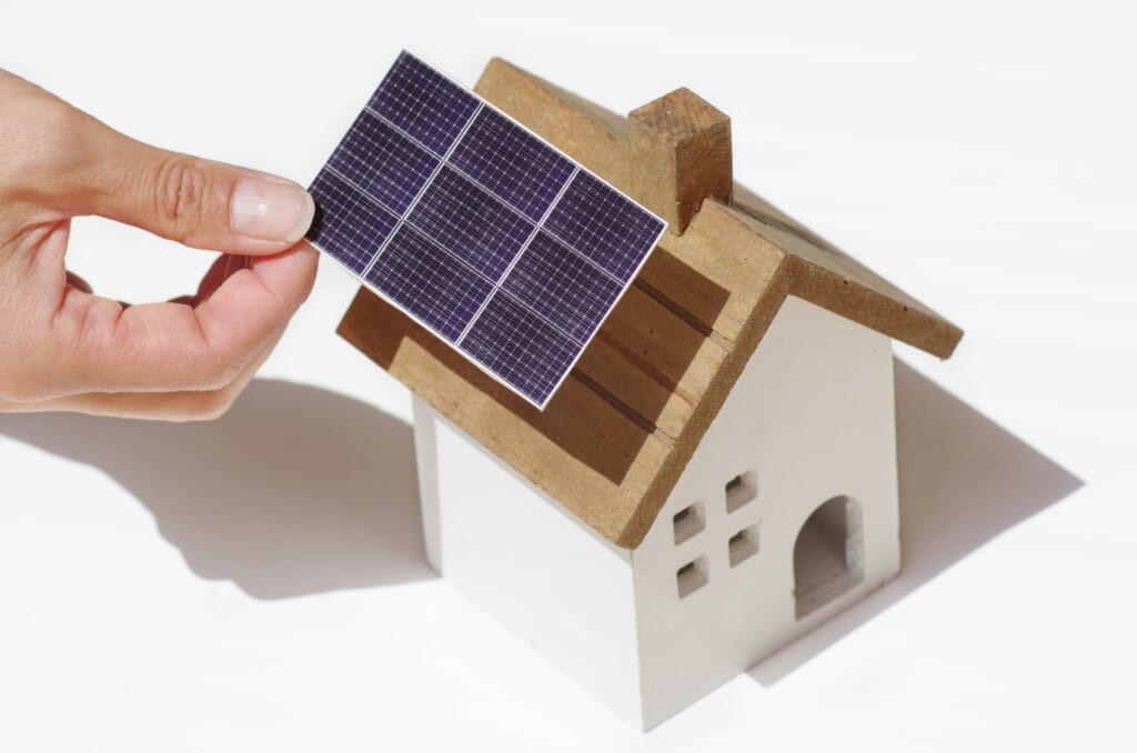 木製の家の形をしたおもちゃと太陽光パネルの模型