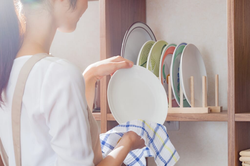 ディッシュラックに食器を拭いて収納する女性