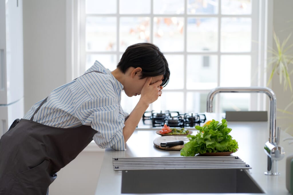 キッチンで頭を抱え込む女性