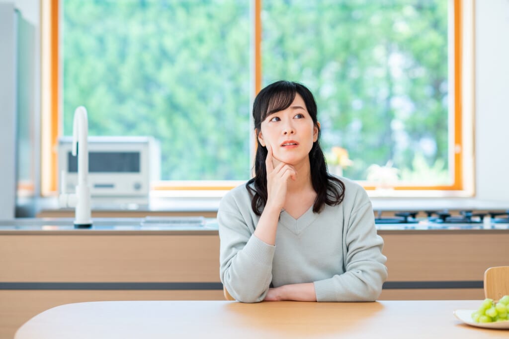 キッチンをバックに考える女性