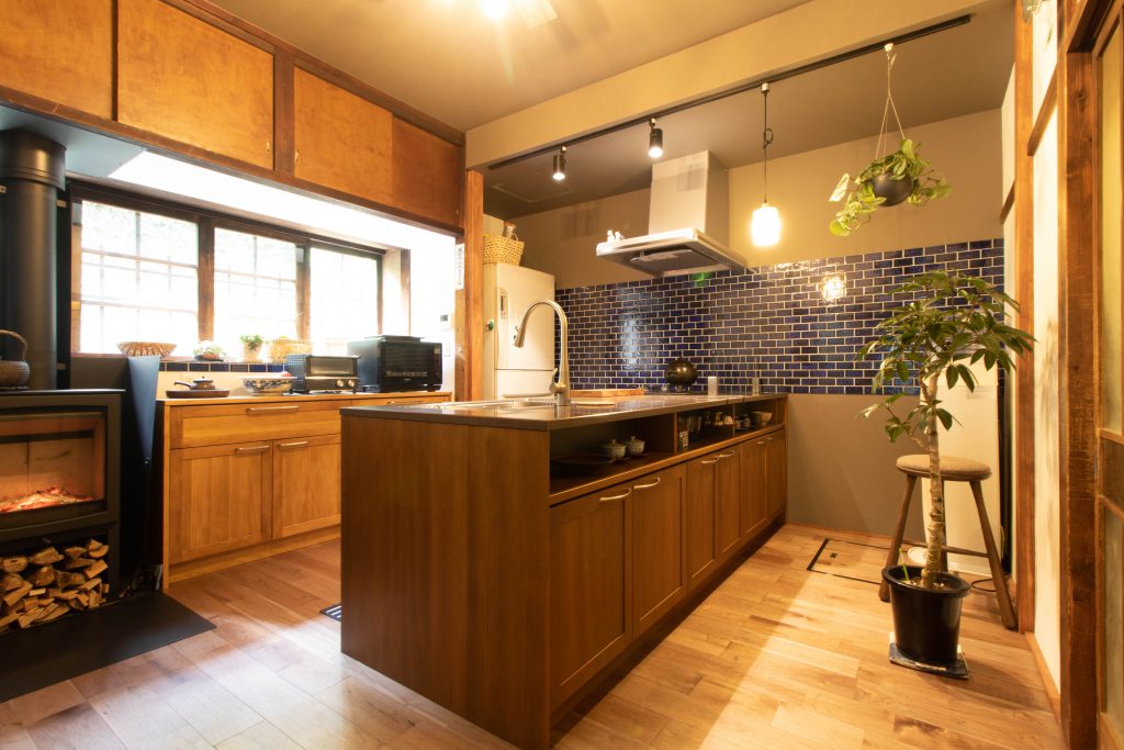 窓から光が差し込むキッチンと薪ストーブ