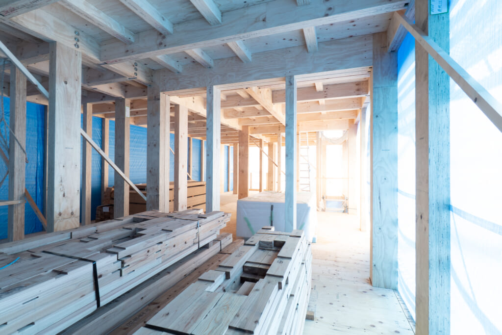 ウッドワンの構造材（JWOOD）が使用された木造建築現場の内部。木材の柱と梁が組み上がり、建設が進められている。